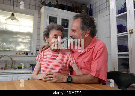 Mère âgée et son fils gay gardien dans la cuisine de leur maison. Katharine Andriotis Banque D'Images