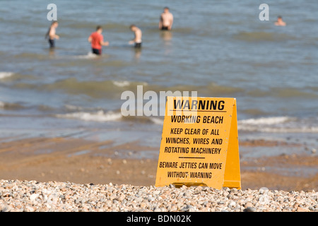 Panneau d'avertissement sur la plage tandis que les gens se baigner. Banque D'Images