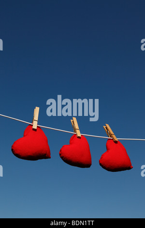 Sacs de fèves en forme de coeur sur une ligne de lavage contre un ciel d'été (version avec les nuages Ref BDNR52) Banque D'Images