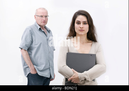 Girl holding un fichier, de sérieux à l'homme à l'arrière Banque D'Images