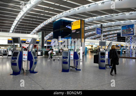 Femme marche passé self service vérifier dans les machines Heathrow Terminal 5 Banque D'Images