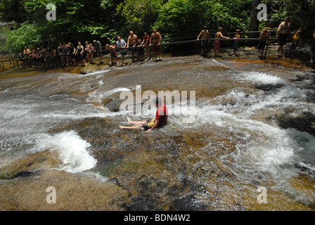 Un jeune garçon glisse vers le bas une roche plate toboggan en Caroline du Nord. Banque D'Images