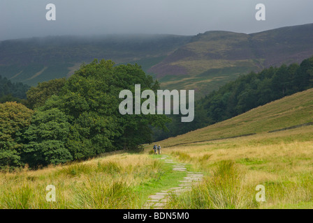 Deux marcheurs sur chemin pavé, au début de la Pennine Way, jusqu'à Kinder Scout, Edale, parc national de Peak, Derbyshire, Royaume-Uni Banque D'Images