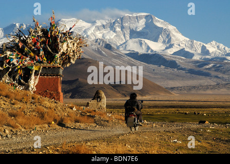 Moto avec deux hommes en face de choerten Tibétain avec les drapeaux de prières en face de la montagne enneigée rance Cho Oyo, 8112 m Banque D'Images