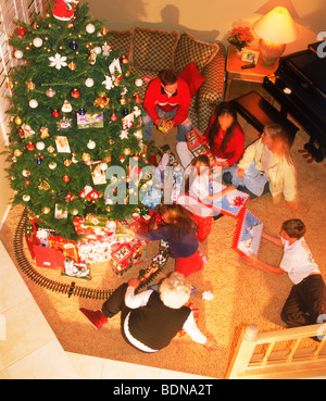 Famille à la maison d'échange présente autour de l'arbre de Noël Banque D'Images