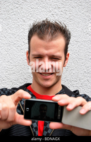 Auto-portrait, jeune homme lui-même photographier avec l'appareil photo de son téléphone portable Banque D'Images
