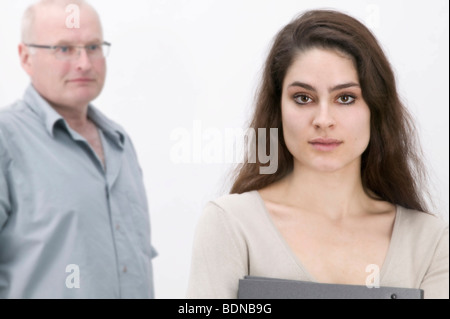 Girl holding un fichier, de sérieux à l'homme à l'arrière Banque D'Images