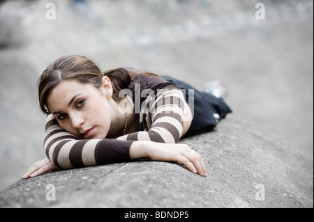 Outdoor portrait d'une jeune fille portant sur le béton à la grave. Banque D'Images