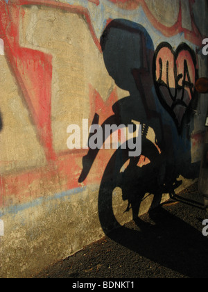 Scooter l'ombre et graffiti sur mur en ville ville Banque D'Images