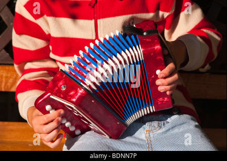 Un modèle a publié neuf ans Garçon jouant un accordéon dans un jardin Banque D'Images