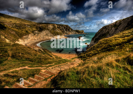 Étapes menant à l'inégale à l'homme de guerre bay dans le Dorset sur un Windy Bay avec rupture de l'eau blanc sur les rochers. Banque D'Images