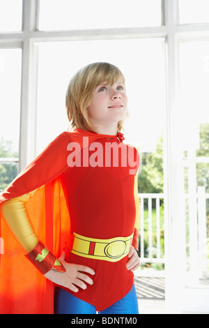 Portrait de jeune garçon (7-9) en costume de super-héro, mains sur la hanche, à l'intérieur Banque D'Images