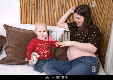 Femme enceinte jouant avec un enfant sur un canapé Banque D'Images