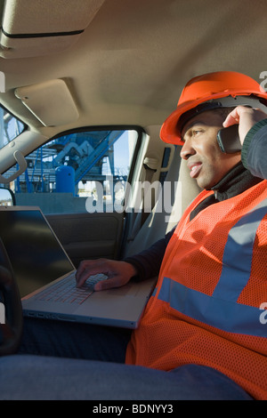 Ingénieur travaillant sur un ordinateur portable dans une voiture Banque D'Images