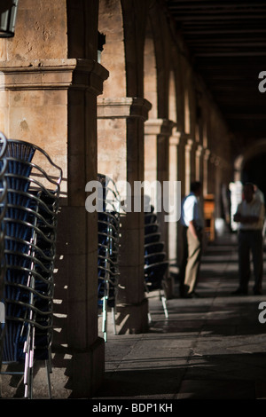 Chaises empilées sous les arcades de la Plaza Mayor, au petit matin, Salamanca, Espagne Banque D'Images