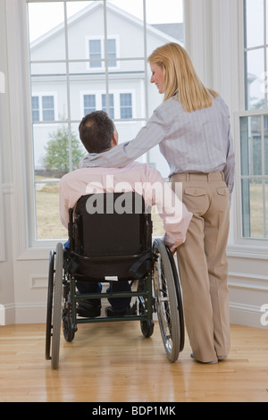 Homme assis dans un fauteuil roulant avec une femme debout à côté de lui Banque D'Images