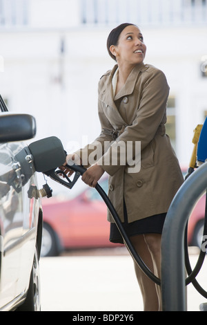 Hispanic woman remplissant une voiture à une station-service Banque D'Images