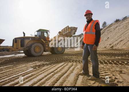 Ingénieur à un chantier de construction d'un chargeur avant à l'arrière-plan Banque D'Images