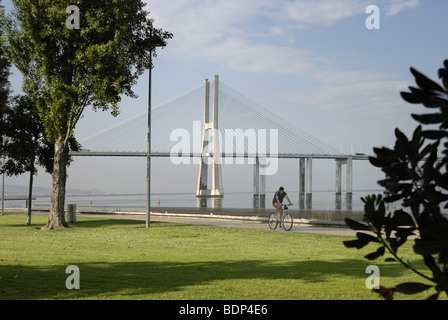 Les cyclistes en face de du pont Vasco da Gama sur le Rio Tejo River dans le Parque das Nacoes Park, site de l'Expo 98, Lisbo Banque D'Images