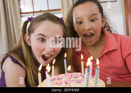 Deux filles blowing out candles sur un gâteau d'anniversaire Banque D'Images