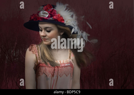 Jeune femme sur un fond sombre, portant des vêtements à l'ancienne, à la réflexion vers le bas Banque D'Images