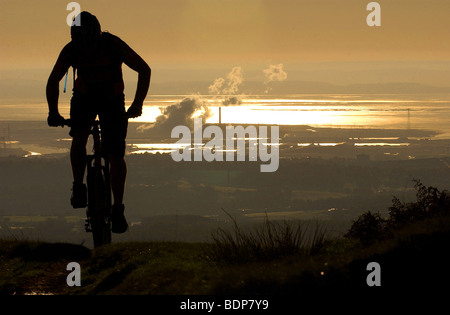 Un cross-country de vélo de montagne grimpe en silhouette comme le soleil se lève sur Newport, Pays de Galles et le Canal de Bristol Banque D'Images