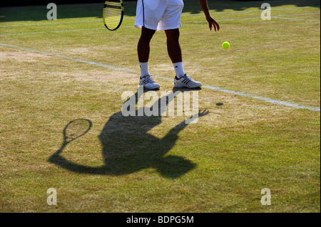 Un joueur et l'ombre qu'il fait rebondir le ballon avant de servir au cours de l'édition 2009 des Championnats de tennis de Wimbledon Banque D'Images