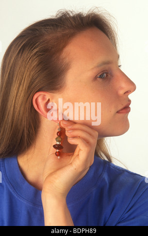 Femme avec une inflammation de l'oreille qui démange souffrant d'une allergie au nickel Banque D'Images