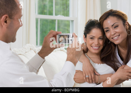Man de prendre une photo de deux femmes hispaniques avec un appareil photo numérique Banque D'Images