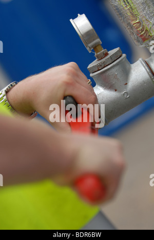 Workman tenant une grande clé clé et tourner une vanne d'eau sur Banque D'Images