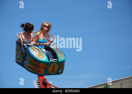 Deux jeunes filles s'amusant à la vapeur à l'ancienne foire avec des manèges nostalgique à Weston Super Mare, Royaume-Uni Banque D'Images