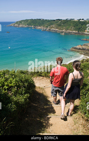 dh Moulin Huet Bay ST MARTIN GUERNESEY Jeune couple touristique marchant le long du sentier de la baie et de la côte sud deux promenade côtière paysage de crique royaume-uni pittoresque Banque D'Images