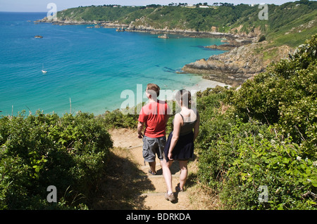 dh Moulin Huet Bay ST MARTIN GUERNESEY Jeune couple touristique sentier pédestre bay coast deux personnes canal îles île côtière promenade le long de la côte Banque D'Images