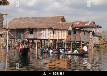 Les enfants de l'école de retour à la maison de l'école élémentaire dans une pirogue de leur servir d'bus quartier montrant leurs maisons o Banque D'Images