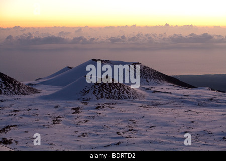 Des cônes sont vus dans la distance entre le sommet du Mauna Kea, à Hawaii, au lever du soleil. Banque D'Images