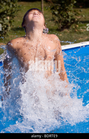 Teenage boy éclaboussures autour de l'eau dans la piscine. Banque D'Images