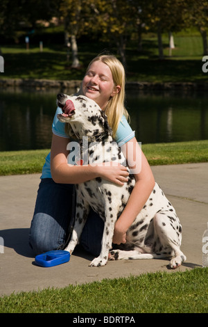 Girl hugging dog enfant 11-13 ans ans jouant propriétaire de chien dalmatien montrer de l'affection side Voir le profil MR © Myrleen Pearson Banque D'Images