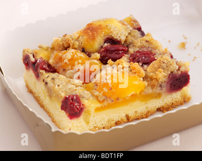 Tranche de gâteau aux abricots, cerises et charlottes sur une assiette en papier blanc Banque D'Images