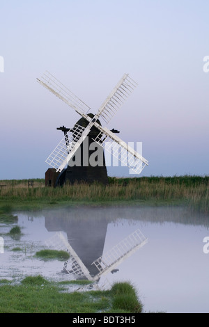 Herringfleet Mill juste après le coucher du soleil avec brouillard passant au large de l'étang de vidange Banque D'Images