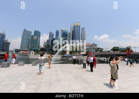 Les touristes de prendre des photos en face de la ville de Merlion derrière, Singapour Banque D'Images