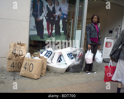 Une femme debout par plusieurs sacs de shopping sur Oxford Street London UK Banque D'Images