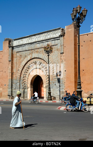 Un homme portant un Jellaba traditionnelle passe devant la porte Bab Agnaou porte dans la ville ou village murs de Marrakech, Maroc Banque D'Images