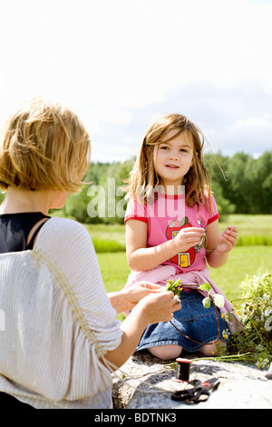 Une fille et une femme faisant des couronnes de fleurs Banque D'Images