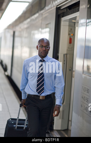 Un homme avec un sac à une station de train Banque D'Images