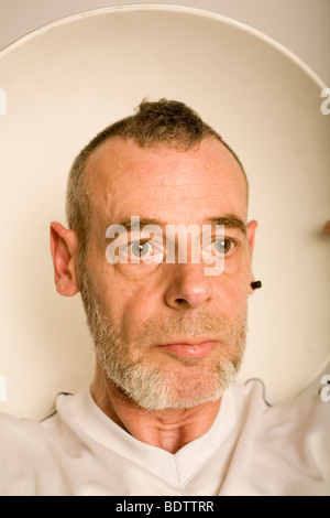 Homme avec un plat de beauté (qui ressemble à un ombrage léger) derrière la tête. Banque D'Images