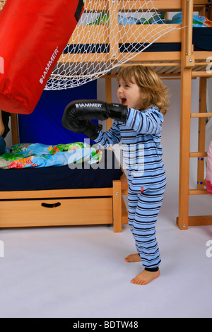 Petit garçon pyjama en formation avec des gants de boxe et sac de boxe d'un Billi-Bolli lit en mezzanine Banque D'Images