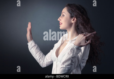 Jeune femme s'étendant la main. Sur fond sombre. Banque D'Images