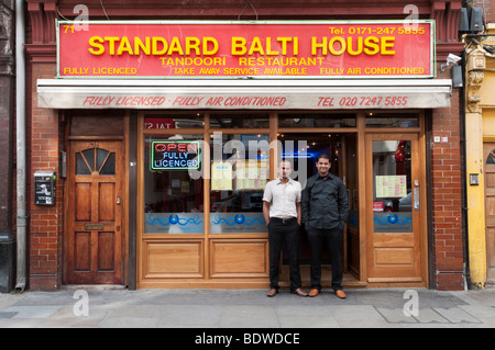 Comité permanent du personnel à l'extérieur de leur curry balti restaurant bangladais et sur Brick Lane, Tower Hamlets, London, England, UK Banque D'Images