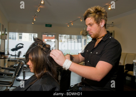 Un adolescent se fait couper les cheveux par un coiffeur dans un salon de coiffure Banque D'Images