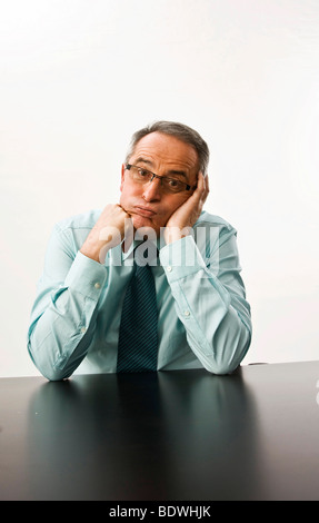 Fatigué manager avec des lunettes assis à son bureau Banque D'Images